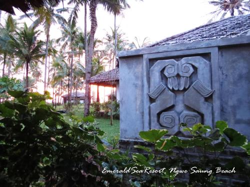 a carving on the side of a building with palm trees at Emerald Sea Resort in Ngwesaung