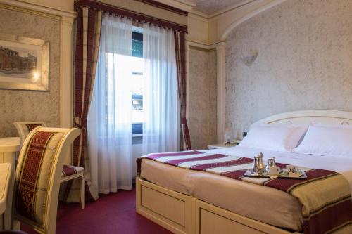 a bedroom with a bed with a window and a table at Hotel Colomba d'Oro in Verona