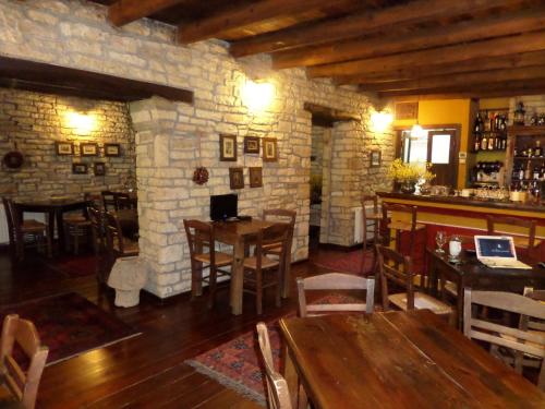 a restaurant with tables and chairs and a stone wall at Arhontiko Aristis in Aristi