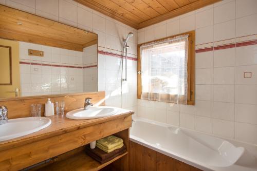 une salle de bain avec un lavabo, une baignoire et un miroir dans l'établissement Le Chalet d'Eléonore, aux Saisies