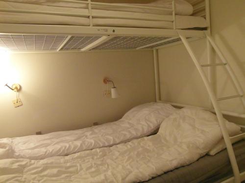 a bedroom with two bunk beds with white sheets at Vigen ferielejligheder in Ebeltoft
