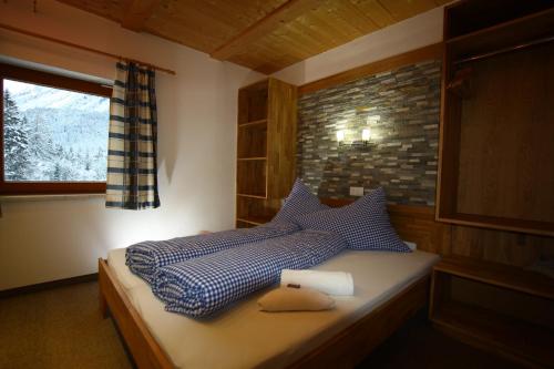 Schlafzimmer mit einem Bett mit blauer Bettwäsche und einem Fenster in der Unterkunft Ferienhaus Panorama in Biberwier