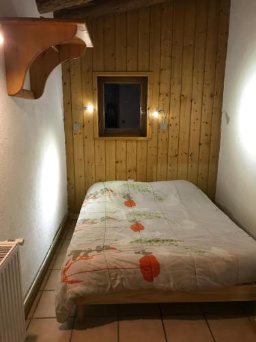 a bed in a room with a wooden wall at Appartement Montgenevre pied de pistes in Montgenèvre