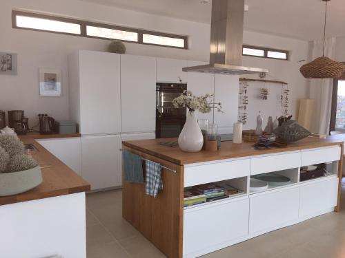 a kitchen with white cabinets and a wooden counter top at Villa Estée, luxury villa with private infinity pool and jacuzzi in Elounda