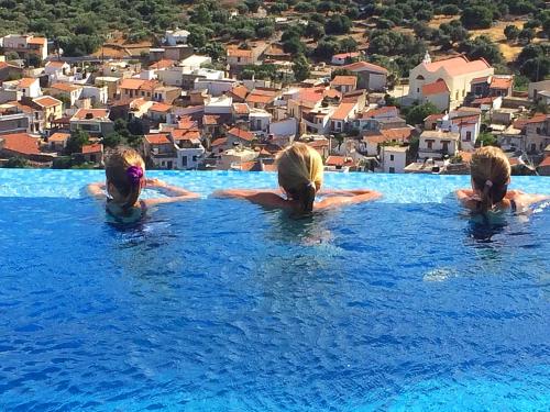 three girls in a swimming pool with a city in the background at Villa Estée, luxury villa with private infinity pool and jacuzzi in Elounda
