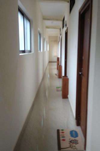 an empty hallway with white walls and windows and a rug at Manjira Lodge in Guruvāyūr