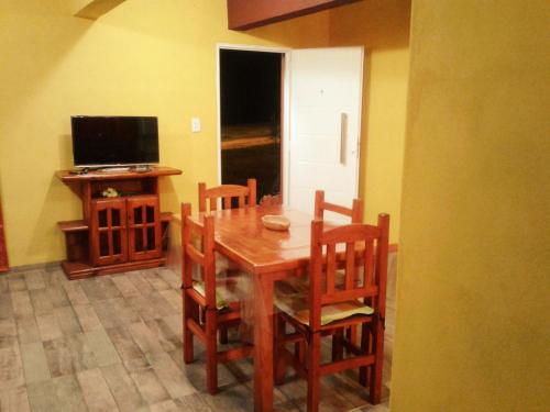 a dining room with a table and chairs and a television at Cabanas Junto al Rio in Panaholma