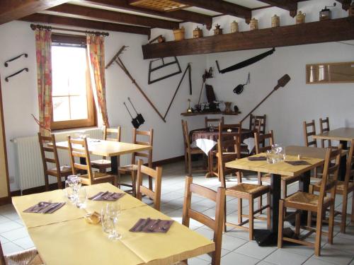 a restaurant with wooden tables and chairs and a window at HOTEL Auberge du grand Git in La Chaux Neuve
