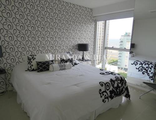 1 dormitorio con 1 cama blanca grande y ventana grande en Apartamento en Punta del Este, en Punta del Este