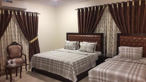 a bedroom with two beds and a chair at Hotel Seven 7 in Karachi