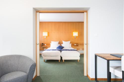 a hotel room with a bed and a chair at Best Western Plus Hotel & SPA Le Schoenenbourg in Riquewihr