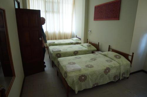 a man standing in a room with two beds at Grand Hotel Mercedes in Pucallpa