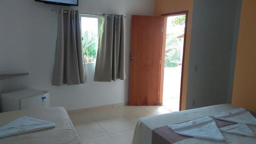a white room with two beds and a window at Pousada Caravelas in Guarapari