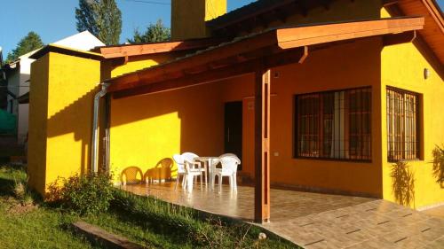 two white chairs and a table on the porch of a house at Cabañas Lomas de Calamuchita in Santa Rosa de Calamuchita