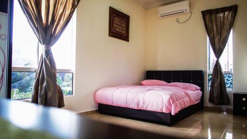Schlafzimmer mit einem Bett mit rosa Bettwäsche und Fenstern in der Unterkunft Family Lodge 25 in Kota Bharu