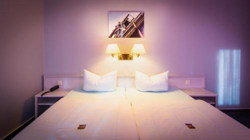 a bedroom with a large white bed with two lamps at Excelsior Bochum in Bochum