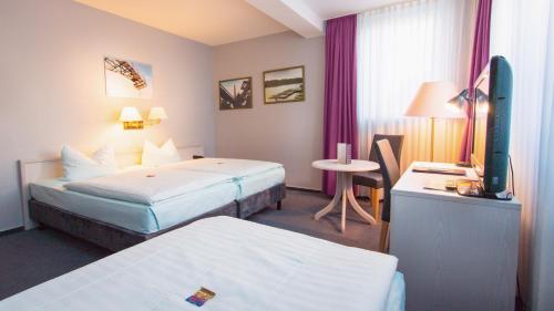 a hotel room with two beds and a television at Excelsior Bochum in Bochum