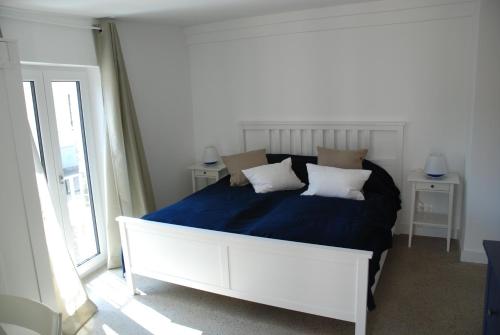 - un lit blanc avec des draps et des oreillers bleus dans une chambre dans l'établissement Remise am Schlosspark, à Schwielowsee