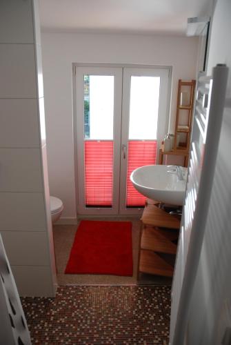 a bathroom with a sink and a toilet and a red rug at Remise am Schlosspark in Schwielowsee