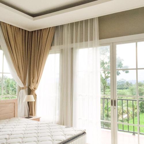 a bedroom with a bed and a large window at Sevilla Resort Magelang in Magelang