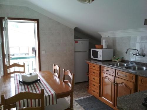 a kitchen with a table and a sink and a microwave at Maison Blanche in Guizande