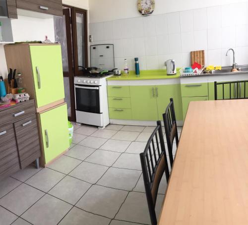 a kitchen with green cabinets and a table and a stove at Habitaciones Valparaiso in Valparaíso