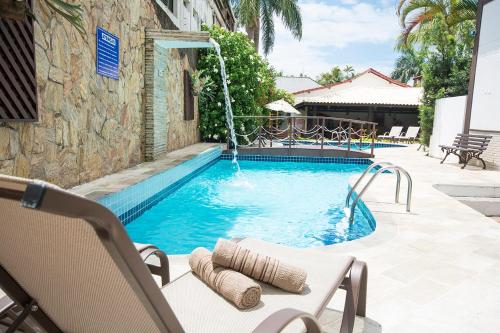 a swimming pool with a fountain in a yard at Hotel Ilhas da Grécia in Guarujá
