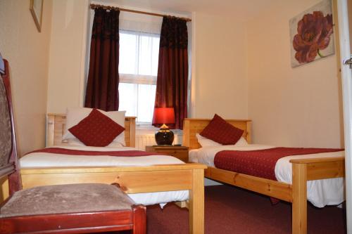 Cette chambre comprend 2 lits et une fenêtre. dans l'établissement Bow Guest House, à Reading