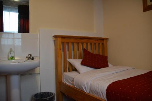 a small bedroom with a bed and a sink at Bow Guest House in Reading