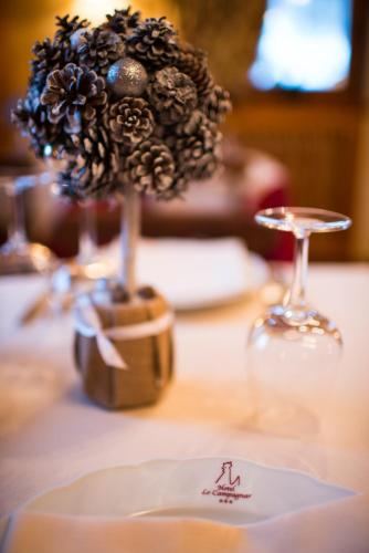 a table with a vase of flowers and a wine glass at Hotel Lo Campagnar in Courmayeur