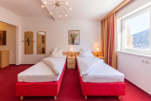 a hotel room with two beds and a window at Hotel Karl Schranz in Sankt Anton am Arlberg