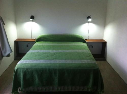 a bedroom with a green bed with two lights on it at Casa en Chapadmalal in Mar del Plata