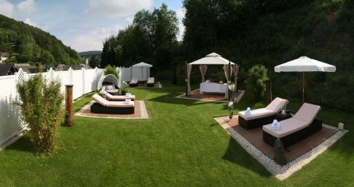 a yard with chairs and umbrellas on the grass at Hotel & SPA Waldecker Hof in Willingen