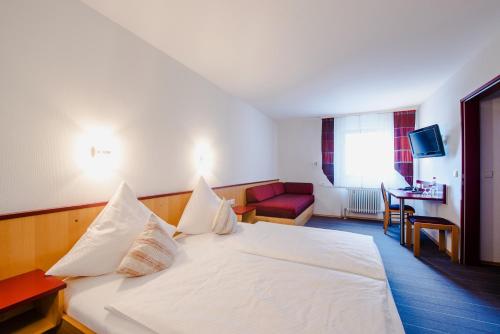 Habitación de hotel con cama blanca y sofá rojo en Hotel Gasthof zum Rössle, en Altenstadt