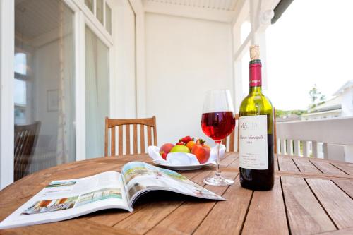 a bottle of wine and a glass on a table with a book at Hotel Villa Belvedere in Binz