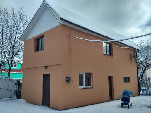 a house with snow on the ground in front of it at Guest House Mandrivnyi Rooms&Apartments in Yasinya