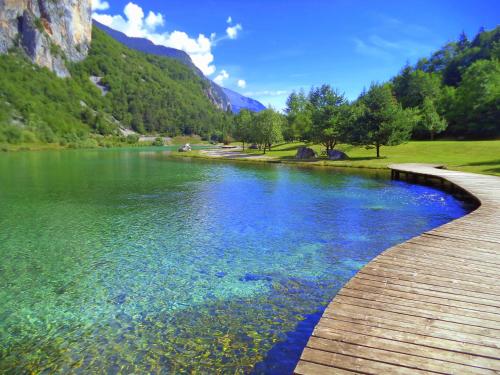 a river with a wooden path next to a mountain at Appartamento Family Park in Andalo