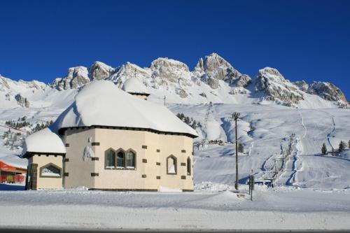 a building in the snow with a mountain in the background at Hotel San Marco in Passo San Pellegrino