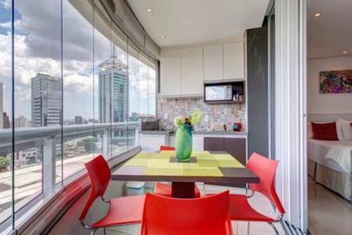 a dining room with a table and chairs and a large window at Be Paulista's Studios in São Paulo