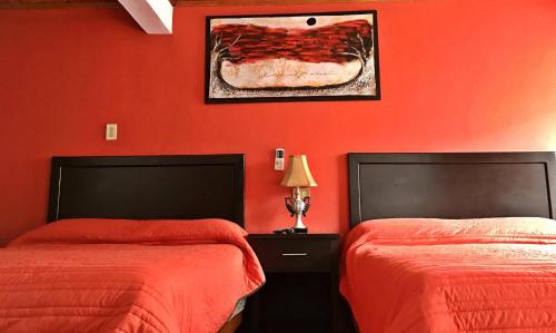 2 Betten in einem Zimmer mit roten Wänden in der Unterkunft Hotel Los Valles in Creel