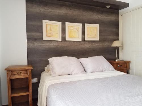 1 dormitorio con 1 cama blanca y 3 cuadros en la pared en New Apartment in the best area en Córdoba