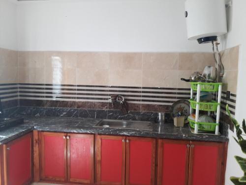 una cocina con armarios rojos y fregadero en joli appartement 4 chambres, en Oujda