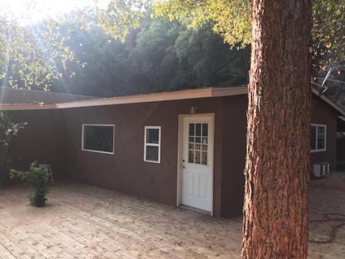 a brown building with a white door and a tree at Mountain Trail Lodge and Vacation Rentals in Oakhurst