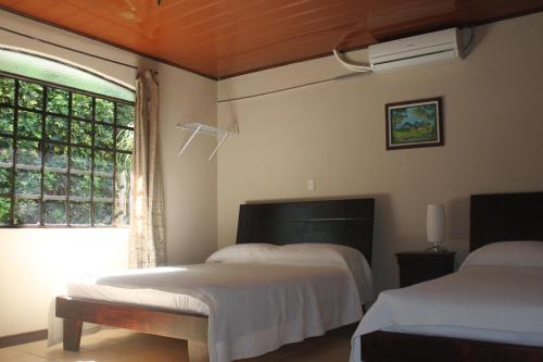 a bedroom with two beds and a window at Hotel Santa Maria Inn in Alajuela