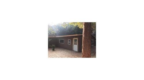 a picture of a house with a tree at Mountain Trail Lodge and Vacation Rentals in Oakhurst