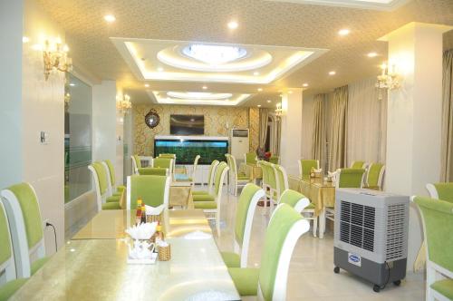 una sala d'attesa con sedie verdi, tavolo e televisore di Minh Hien Hotel a Phan Thiet