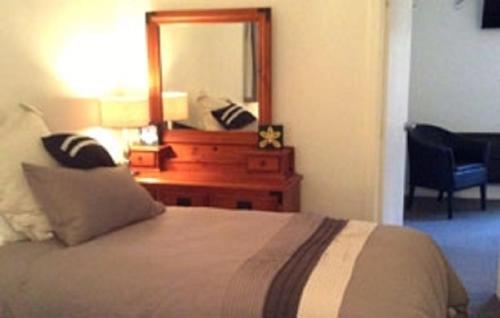 a bedroom with a bed and a dresser with a mirror at Noah's Boutique Accommodation Moeraki in Moeraki