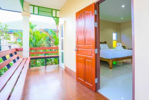 a door leading to a bedroom with a bed and a balcony at Huan Soontaree in Ban Phe