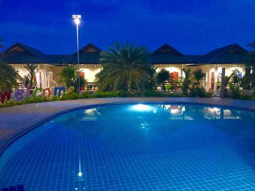 a swimming pool in front of a house at night at Huan Soontaree in Ban Phe