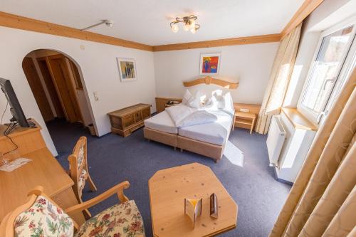 a bedroom with a bed and a desk and a table at Hotel Karl Schranz in Sankt Anton am Arlberg